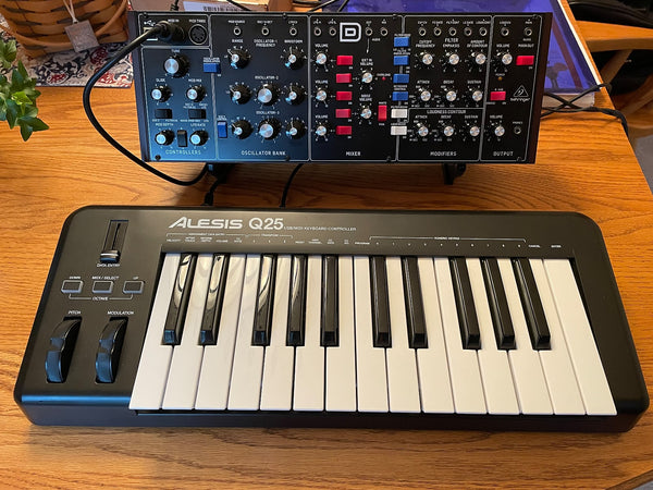 Single tier KVgear stand for Behringer Model D, with Alesis Q25 on table in front.  Plenty of room for cables to pass underneath.