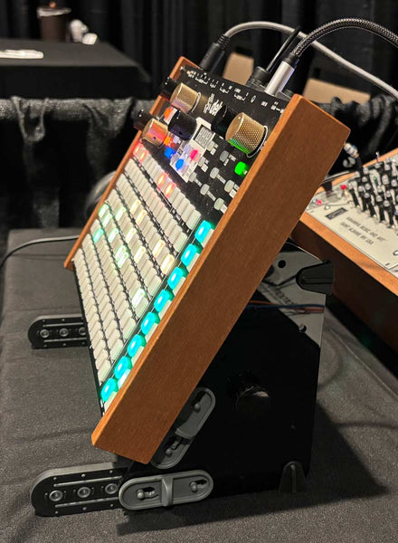 Side view of Synstron Deluge on SynthRISE steeply angled stand, with base stabilizer bars visible at the front.