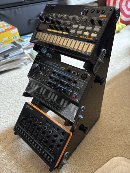 SynthRISE Adapt Small 3 tier desktop synth stand holding a Korg Volca, Behringer mini, and Roland Compact synths.